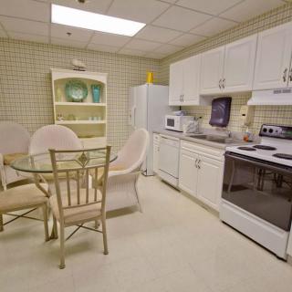 A modern kitchen with white cabinets, a dining table, and various appliances.