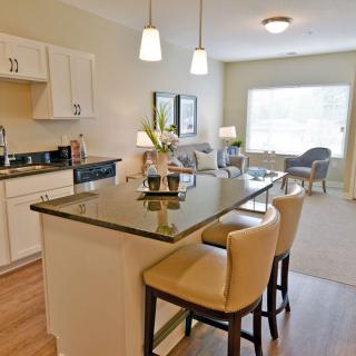 A modern open-concept kitchen with an island and dining area, featuring pendant lighting and counter stools.