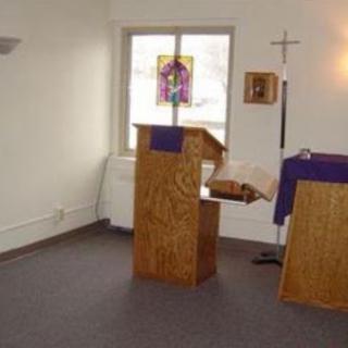A serene interior view of a chapel with a wooden pulpit and altar, adorned with purple cloth.