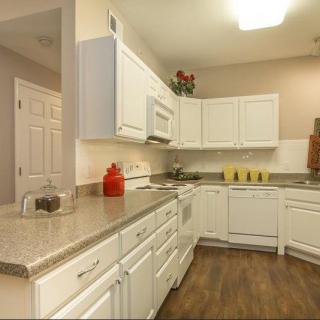 A modern kitchen with white cabinets and hardwood flooring.