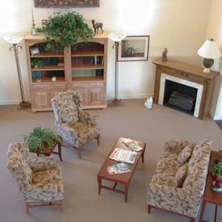 A cozy living room with floral-patterned furniture and a fireplace, featuring a coffee table and bookshelf.