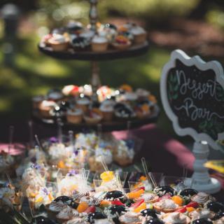 A beautifully arranged dessert table at an outdoor event featuring cupcakes and sweets on a multi-tier cake stand.