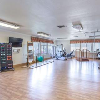 A spacious gym equipped with various exercise machines and weights, ideal for fitness and rehabilitation.
