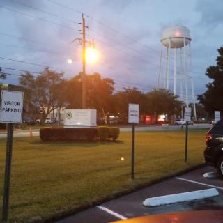 Evening scene of a parking lot with street lights and a distant water tower.
