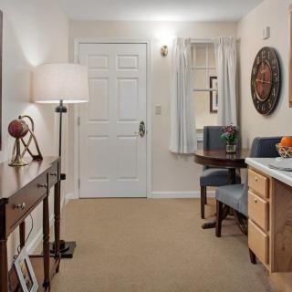 A cozy living room area featuring a desk, lamp, and decorative items.
