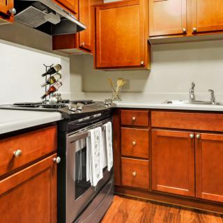 A cozy kitchen with wooden cabinets featuring a stove, oven, and sink.