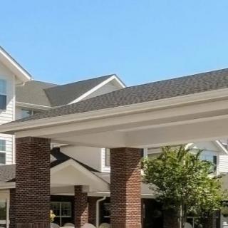 A residential building with brick columns and a pitched roof under a clear blue sky.