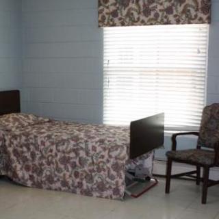 A simple room with a bed, chair, and window.
