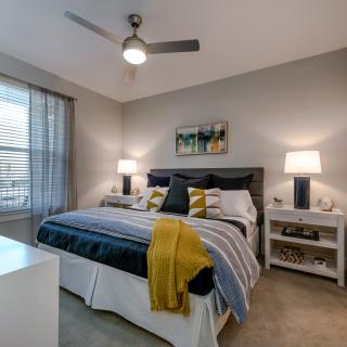 A modern bedroom with a double bed, stylish bedding, two lamps on nightstands, and artwork above the headboard.