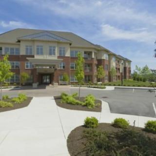 A modern residential apartment building with landscaped surroundings and a parking lot.