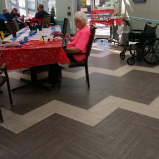 A cozy indoor space at a care facility, featuring tables with festive decorations and seating for residents.
