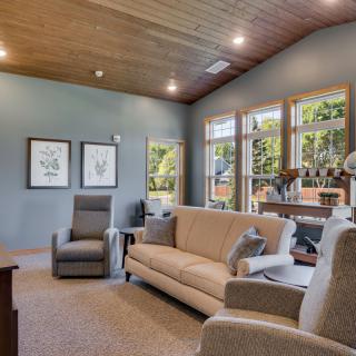 A cozy living room featuring a sofa, armchairs, and large windows allowing natural light to brighten the space.
