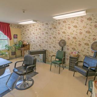 Cozy hair salon setup with floral wallpaper and chairs.