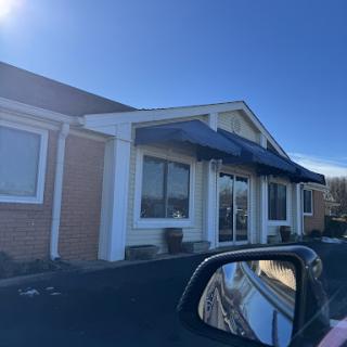 A clear view of a building with a blue awning on a sunny day.