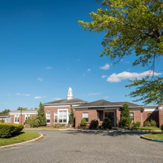 A brick building with a central entrance and a clear blue sky in the background.