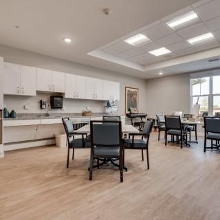 A modern kitchen and dining area with tables and chairs, featuring bright lighting and a spacious layout.