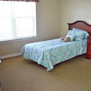 A simple bedroom with a single bed and patterned bedding near a window.