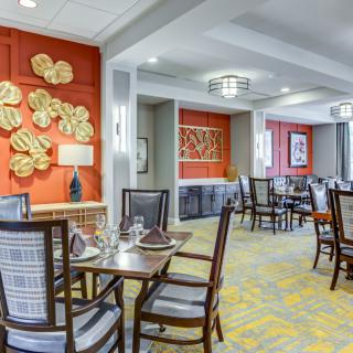 A modern dining room with elegant decor, featuring tables and chairs, vibrant artwork, and sophisticated lighting.