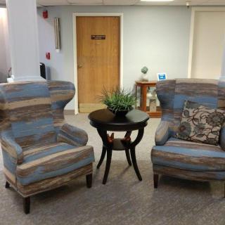 A cozy waiting area with two striped armchairs and a small round table.