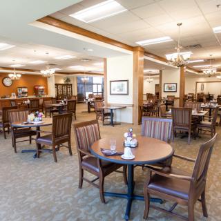 A spacious dining area featuring wooden tables and chairs, with warm lighting and an inviting atmosphere.