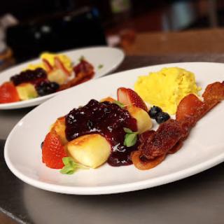 A delicious breakfast featuring a colorful fruit medley, scrambled eggs, and crispy bacon.