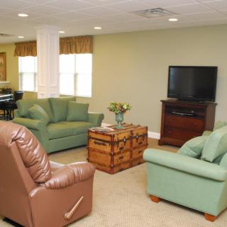 A cozy living room with a sofa set, armchair, and television.