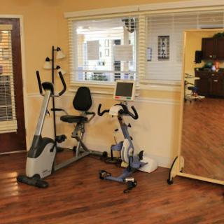 A cozy home gym featuring an exercise bike, an elliptical machine, and a large mirror for workouts.