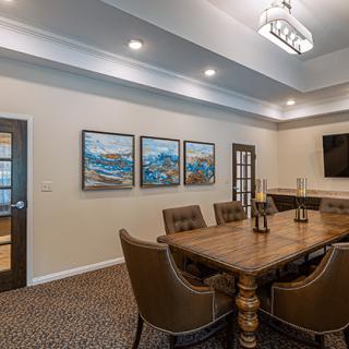 A modern conference room featuring a long table with chairs, artwork on the walls, and ceiling lighting.