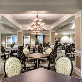 Elegant dining room with multiple tables and chairs, featuring a central chandelier.