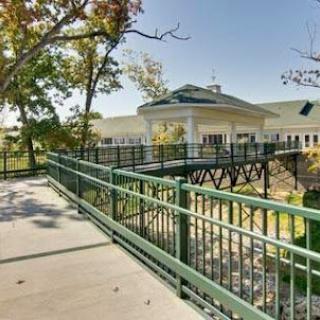 A scenic view of a bridge leading to a modern building surrounded by trees.