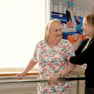 A caregiver assists a patient in a rehabilitation setting, promoting mobility and support.