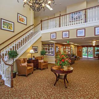 A cozy lobby area with elegant decor, featuring a staircase, comfortable seating, and vibrant plants.
