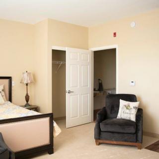 A cozy bedroom with a bed, an armchair, and an open closet door.