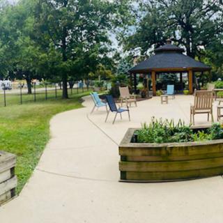 A serene park setting with a gazebo and seating area surrounded by trees.