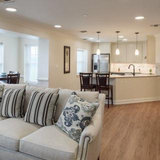 A modern open floor plan featuring a cozy living room and sleek kitchen with wood flooring.