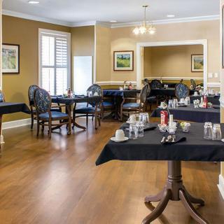 An elegant dining room with neatly arranged tables and chairs, featuring large windows and tasteful decor.