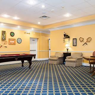 A cozy game room featuring a pool table, shuffleboard, and comfortable seating with wall decorations.