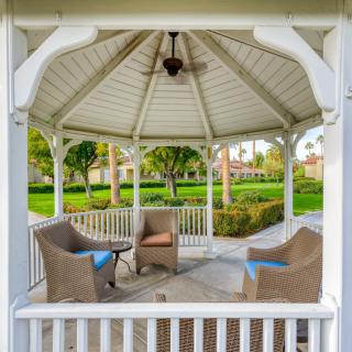 An inviting gazebo with wicker chairs set amidst a lush garden.