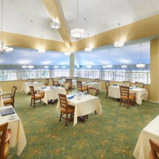 Spacious dining area with neatly arranged tables and chairs, featuring ample lighting and large windows.