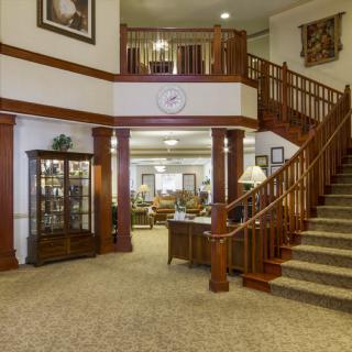 A spacious, elegantly designed lobby with a grand staircase and wooden furnishings.