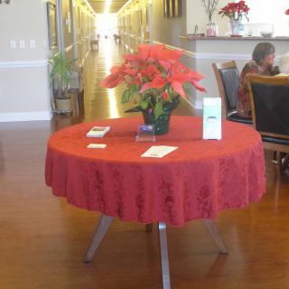 A round table with a red tablecloth and a poinsettia centerpiece in a lobby area.