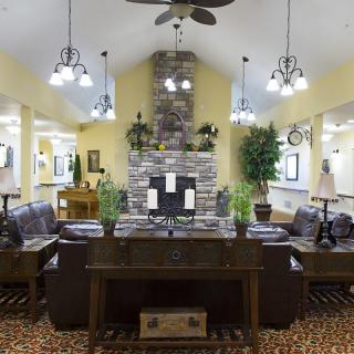 A cozy living room with a stone fireplace, comfortable seating, and elegant lighting.