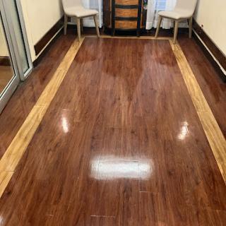 A well-polished wooden floor with a decorative border, complemented by two chairs in the background.
