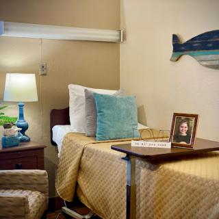 A cozy hospital room designed for comfort, featuring a neatly made bed, a bedside lamp, and personal touches like a photo frame.