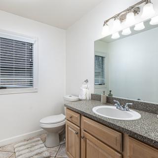 A clean and bright bathroom with a large mirror and granite countertop.