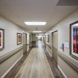 A long, brightly lit hospital hallway adorned with artwork on the walls.