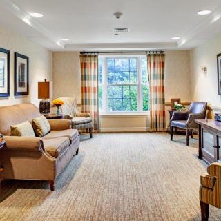 A cozy living room with a sofa, chairs, and large window with curtains.