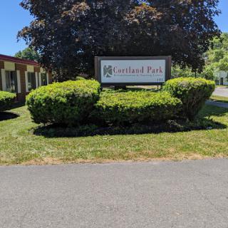 Entrance sign of a park surrounded by well-maintained shrubs and grass.