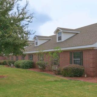 A row of brick houses with well-maintained landscaping and a grassy yard.