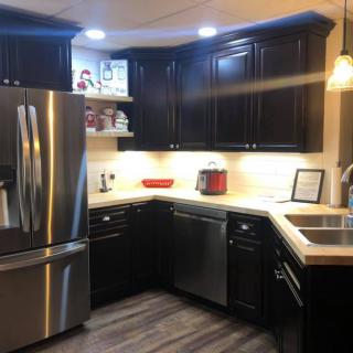 A modern kitchen with dark cabinets and stainless steel appliances.